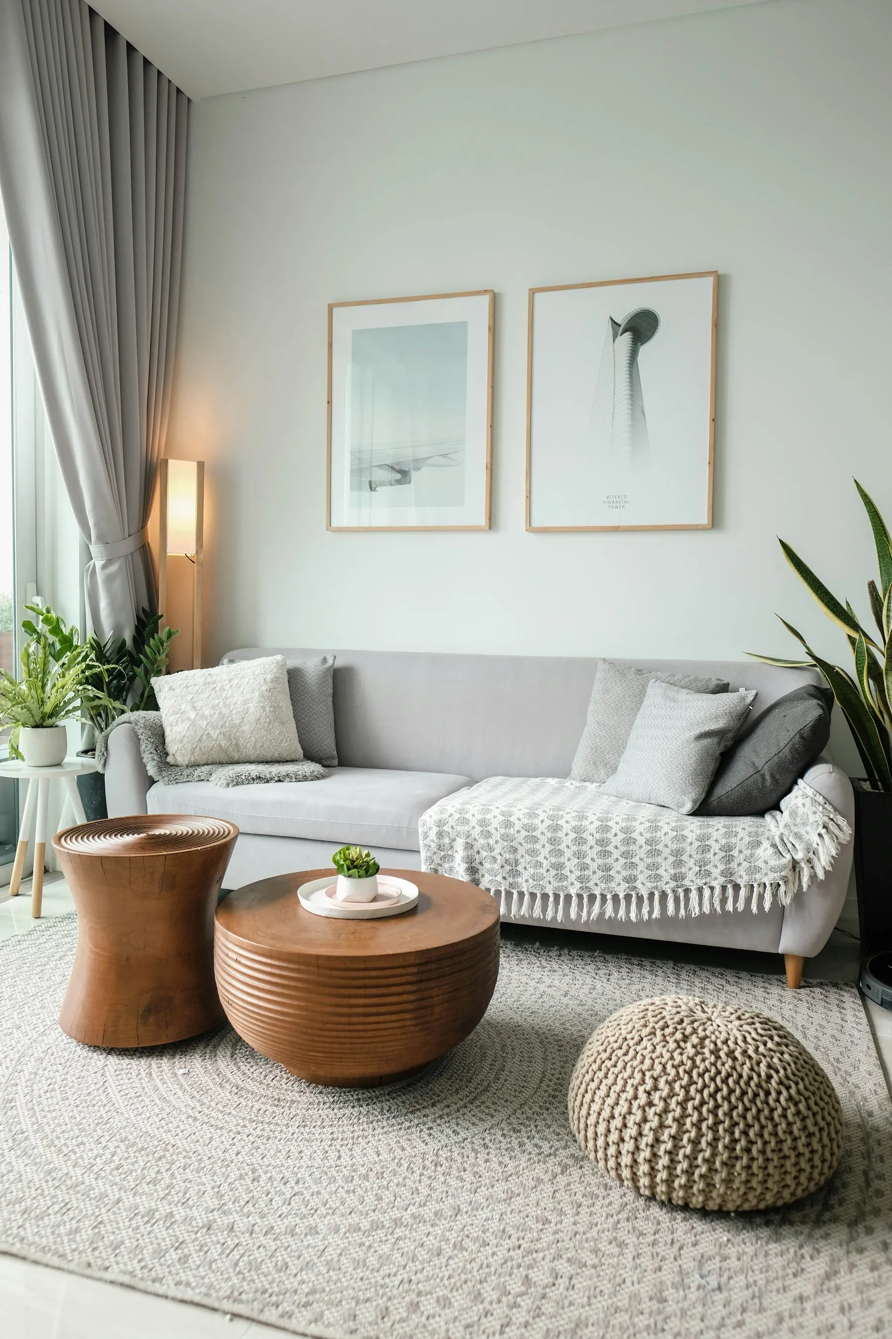 Salon lumineux d'un appartement avec canapé gris et tables en bois