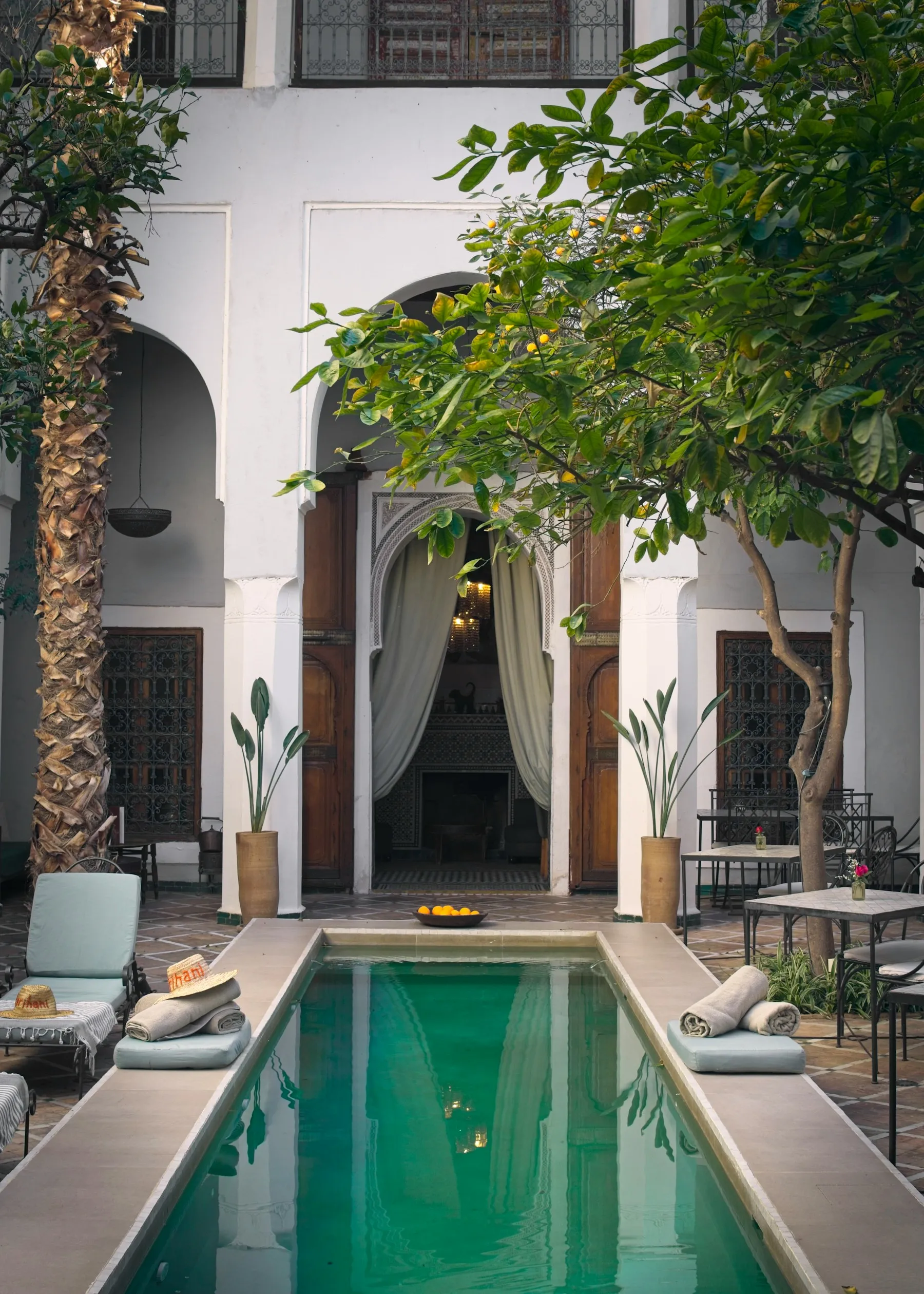 Patio d'un riad avec bassin, orangers et arches à Marrakech